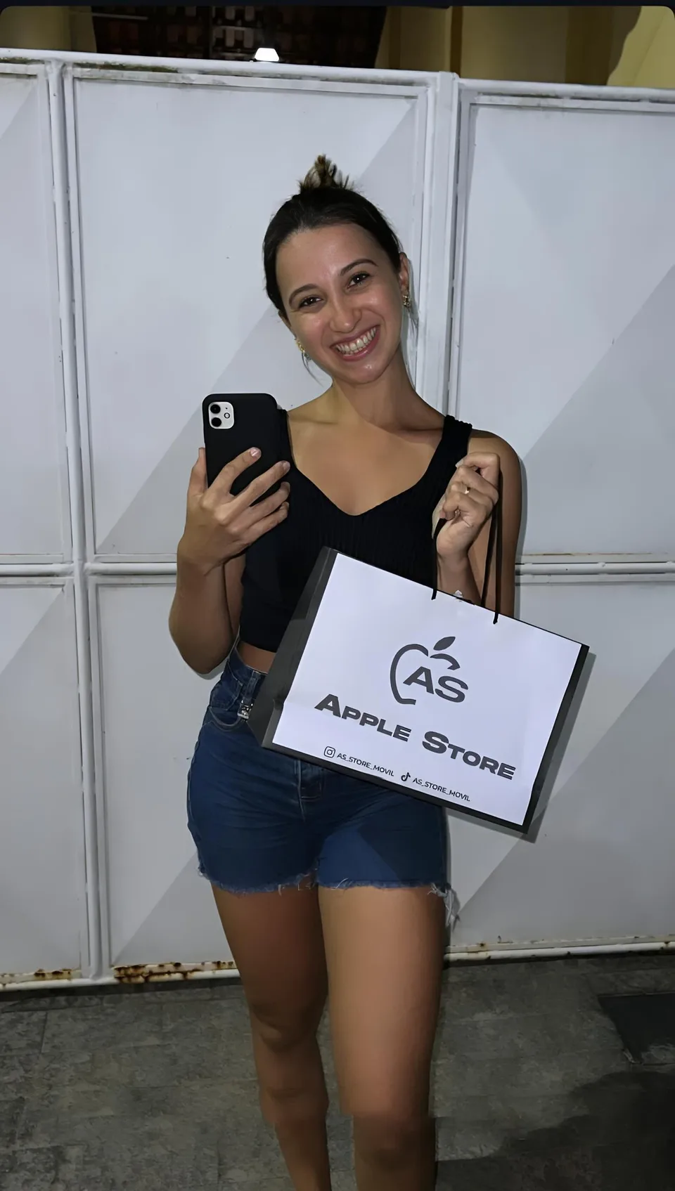 Clienta con teléfono y bolsa de AS Store Móvil